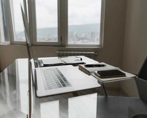 A glass table top with notebooks and pens next to a sunny window layout