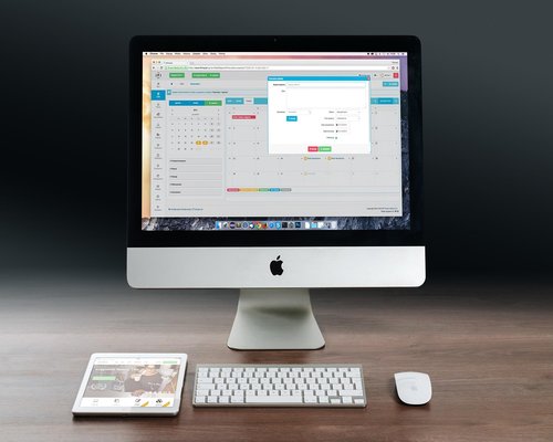 A laptop screen glowing on a tidy wooden desktop setup with warm secondary ambient light